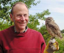 man in red sweater holding an owl