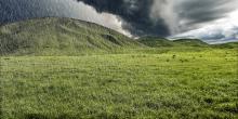 grassy hillside with dark clouds