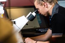 man looks into microscope