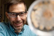 Scott Baker in protective eyewear behind fungi sample