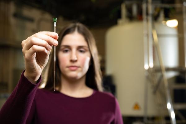 Elizabeth Eder holds a component to the liquid nuclear magnetic instrumentation.
