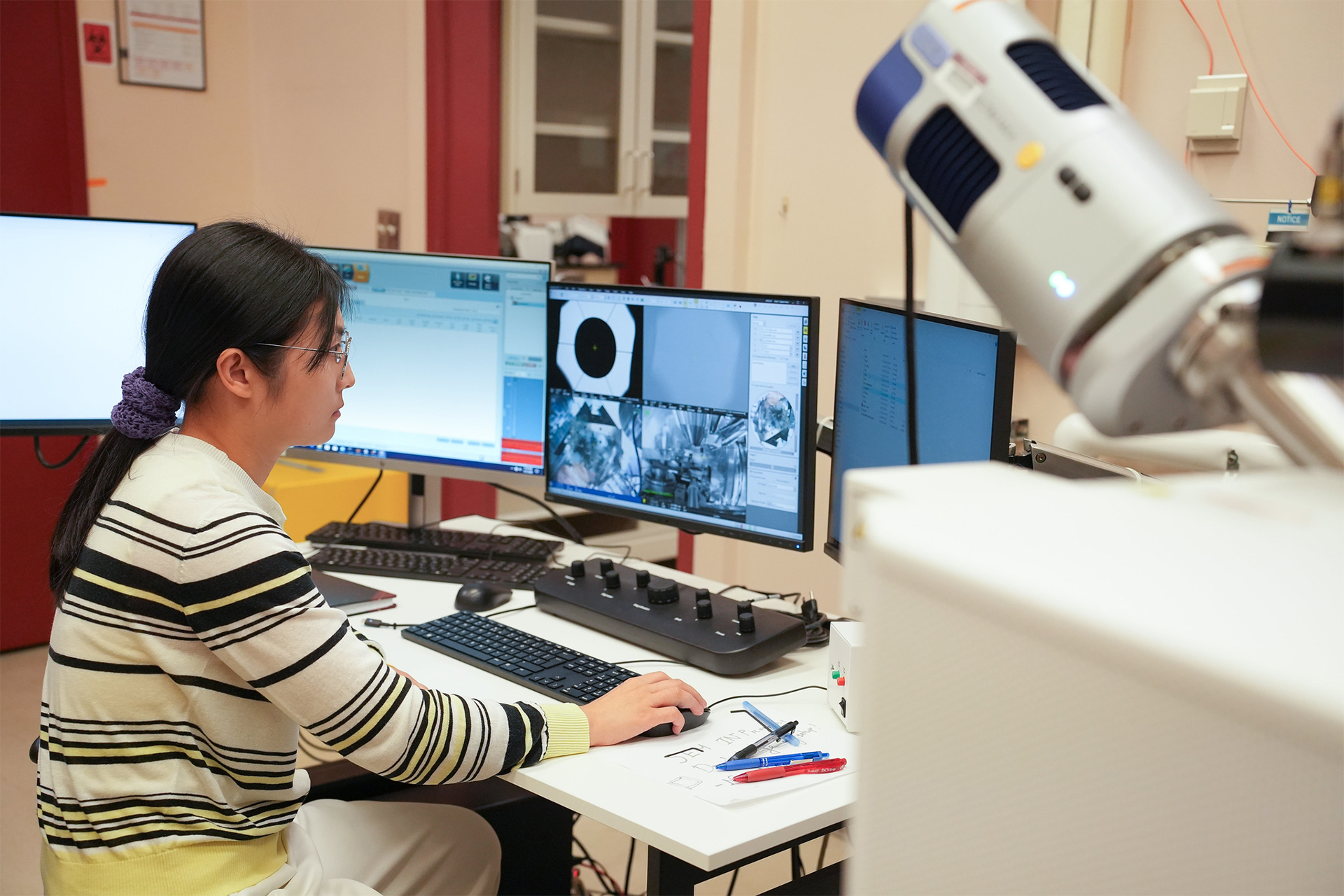 Photo of researcher Theia Moon seated at a laboratory station, looking at a computer monitor.