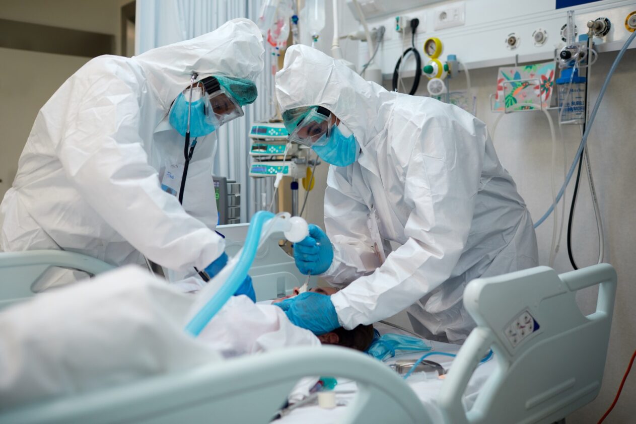 people in full gowns and protective wear work on a COVID patient in a hospital.