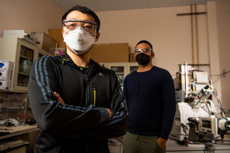 two men are wearing protective eye wear and masks inside a laboratory