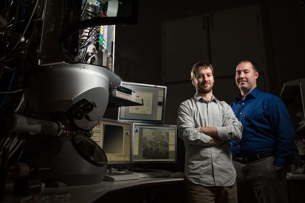 Image of James Evans and Trevor Moser posing by the Cryo-TEM instrument.