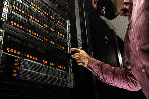 Person wearing mask stands near Tahoma supercomputer