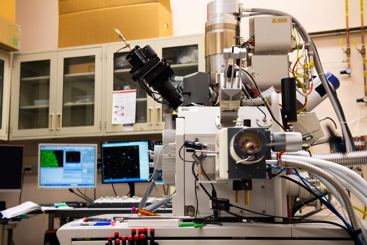 photo of microscope with computers behind it