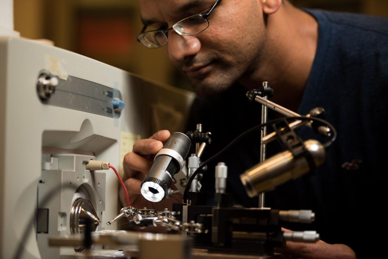 Photo of Swarup China looking through a microscope