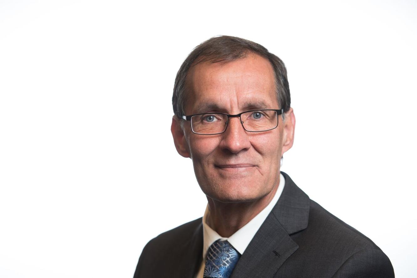 photo of man with glasses wearing a tie and a black suit