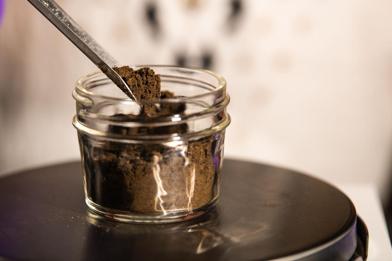 soil in a glass jar is removed with a metal instrument