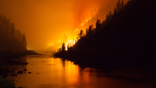 wildfire on hillside near body of water