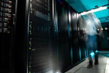 A person walks beside computing towers that comprise the Tahoma high-performance computer. The person appears blurred as they walk by.