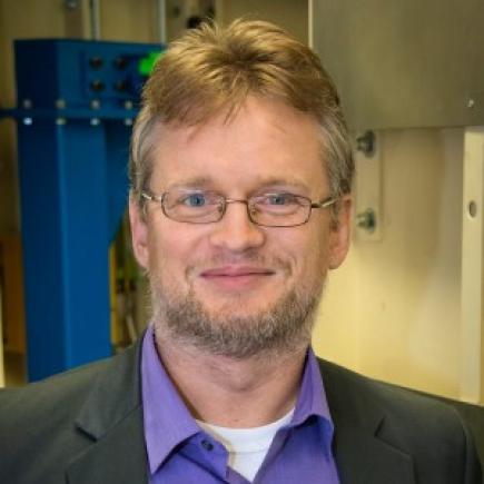 Photo of researcher Peter Zwart in a purple dress shirt, black blazer, and glasses